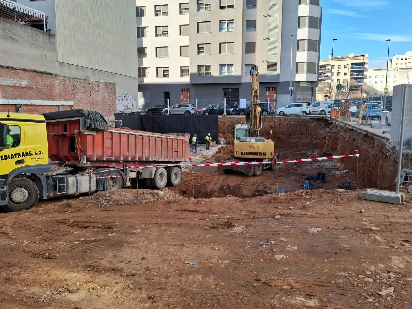 Wykopy i prace ziemne przy budynku Luz Koparka i ciężarówka podczas prac wykopowych przy budynku Luz, z pracownikami na placu budowy.