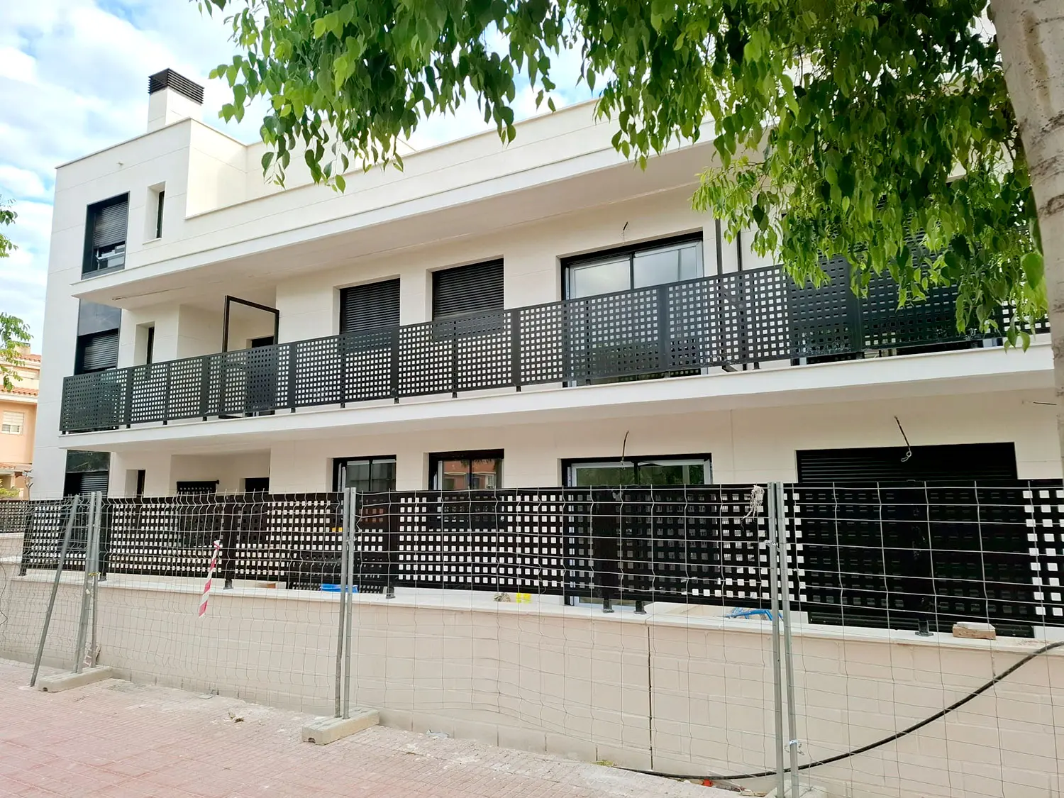 A Lledó Auditorium építési előrehaladása, befejezett homlokzattal és végső részletekkel Lledó Auditorium épület, előrehaladott építési munkák, modern fehér homlokzat és fém erkélyek