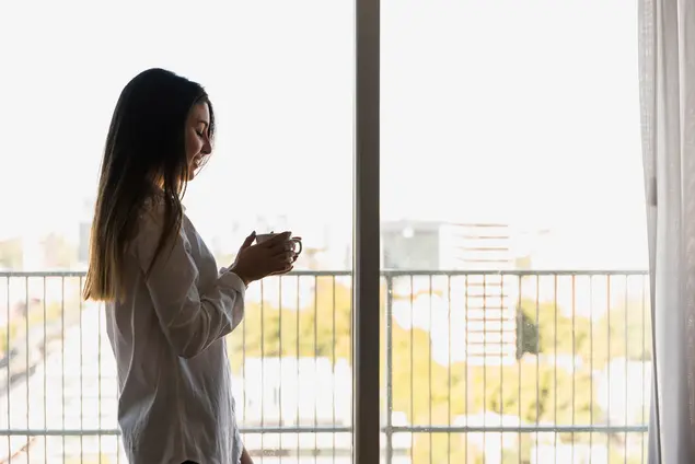 Apartamente noi în Castellón, cu vedere și lumină naturală O femeie se bucură de balconul luminos al unui apartament nou construit în Castellón, cu vedere spre oraș